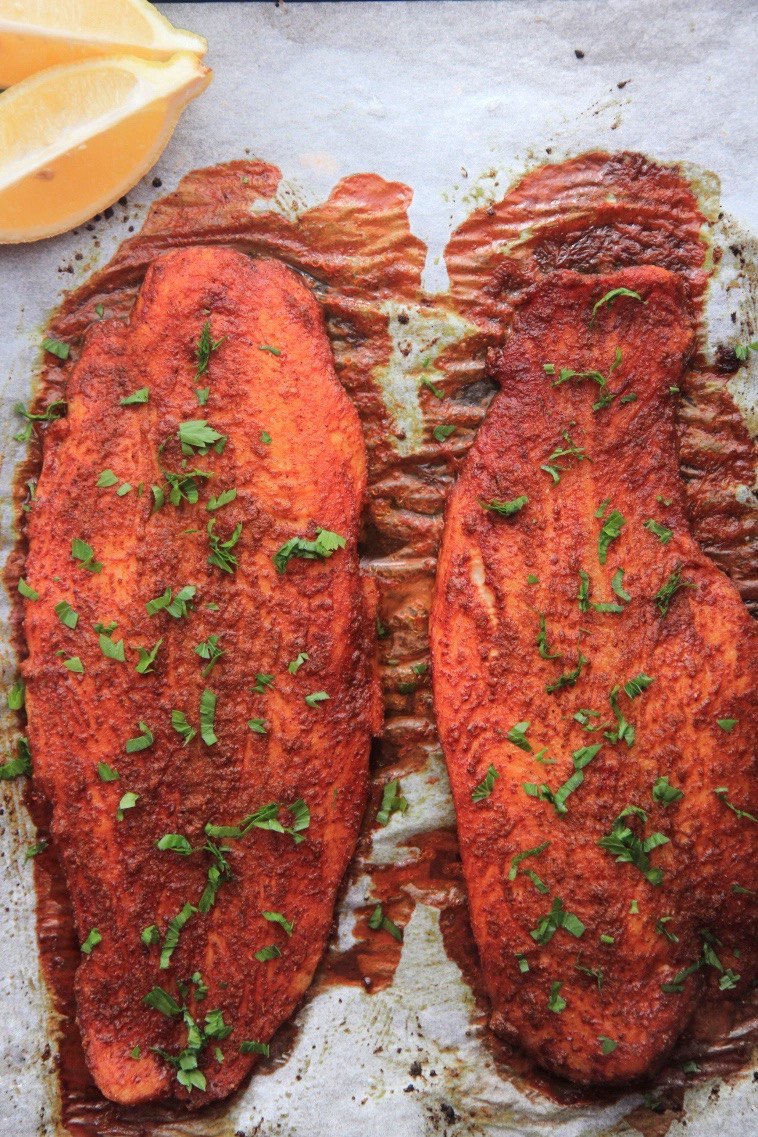 Two tandoori fish fillets garnished with parsley and lemon wedges.