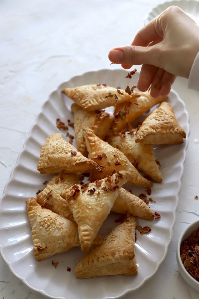 Garnishing a platter of hand pies with rose petals.