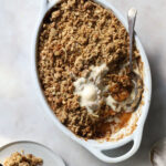 Top down image of apple crumble with a scoop of melting ice cream.