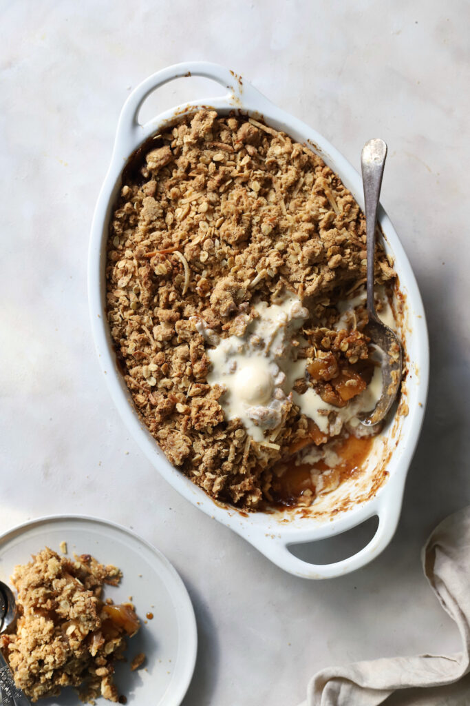 Top down image of apple crumble with a scoop of melting ice cream.