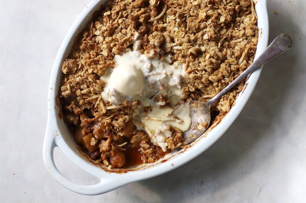 Apple crumble with a scoop of ice cream in an oval baking dish.