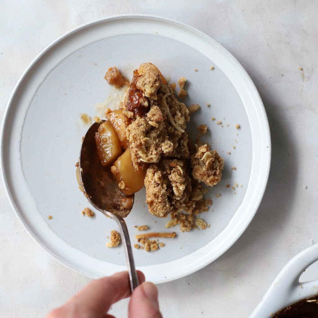 Top down image of a scoop of crumble being served on a plate.