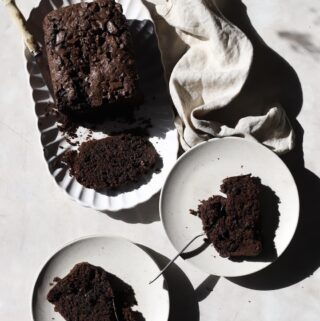The sliced chocolate zucchini loaf with a piece in each of the two side plates.