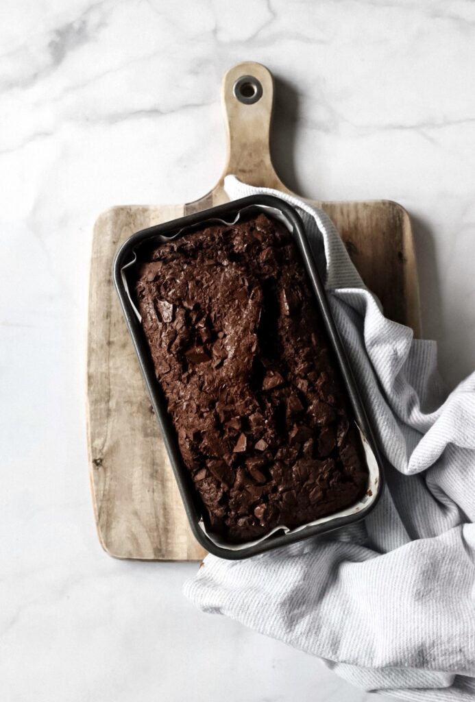 A freshly baked loaf of double chocolate zucchini bread, on a cutting board.