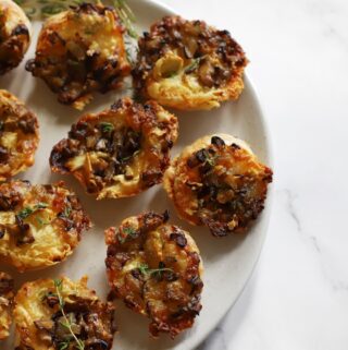 Baked Camembert and mushroom tartlets served warm on a plate.